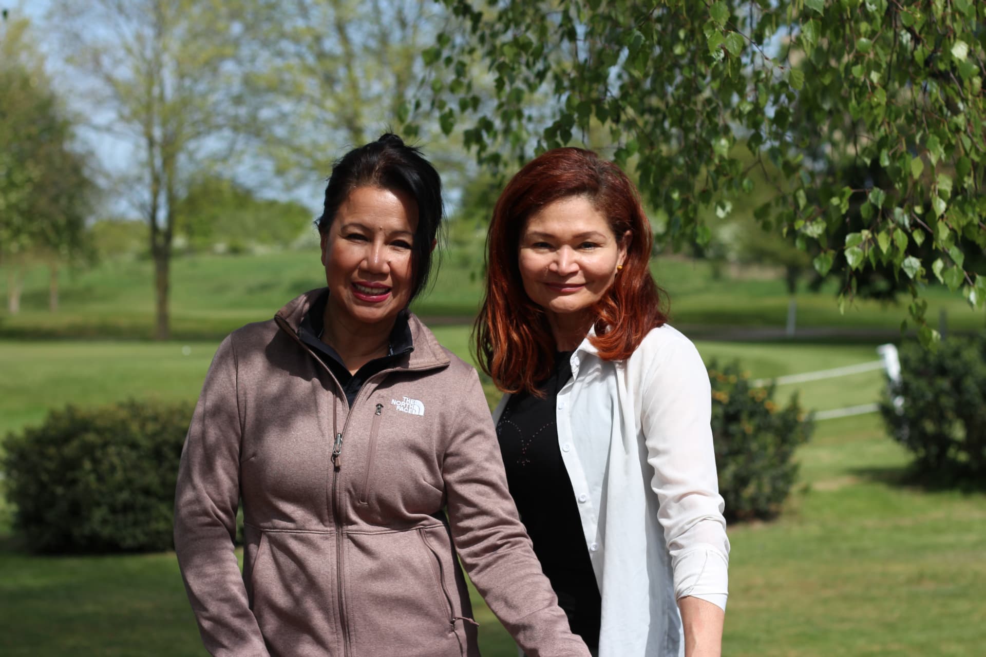 Adriana and Rebecca smiling together outdoors in the sunshine